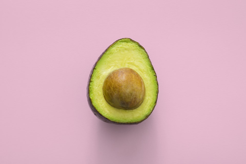 A sliced avocado kept away from a cat